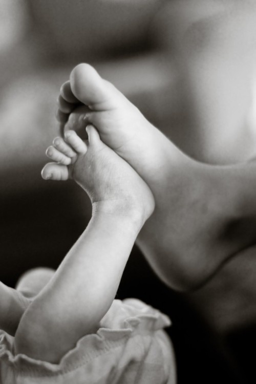pied d'un bébé contre le pied d'un parent
