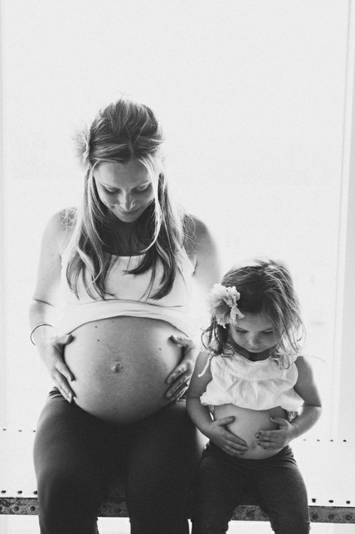 Une maman enceinte et sa fille qui se touche le ventre